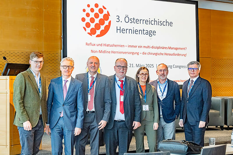 Gruppenfoto von sieben Teilnehmenden der 3. Österreichischen Hernientage 2025 vor einer Projektionswand mit dem Veranstaltungstitel im Salzburg Congress.